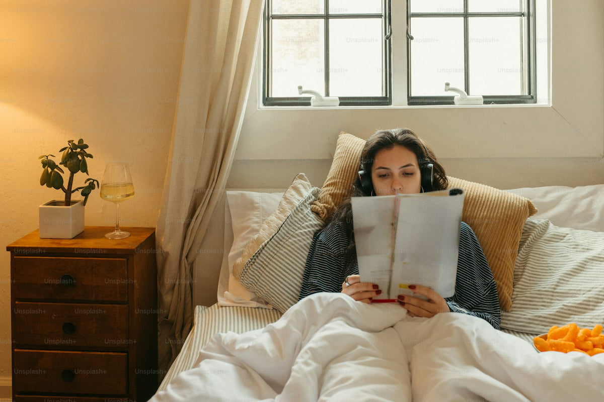 Woman reading in bed with headphones on, a cozy scene of alone time