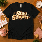 Stay Souper food graphic t-shirt cozy flat lay in black.