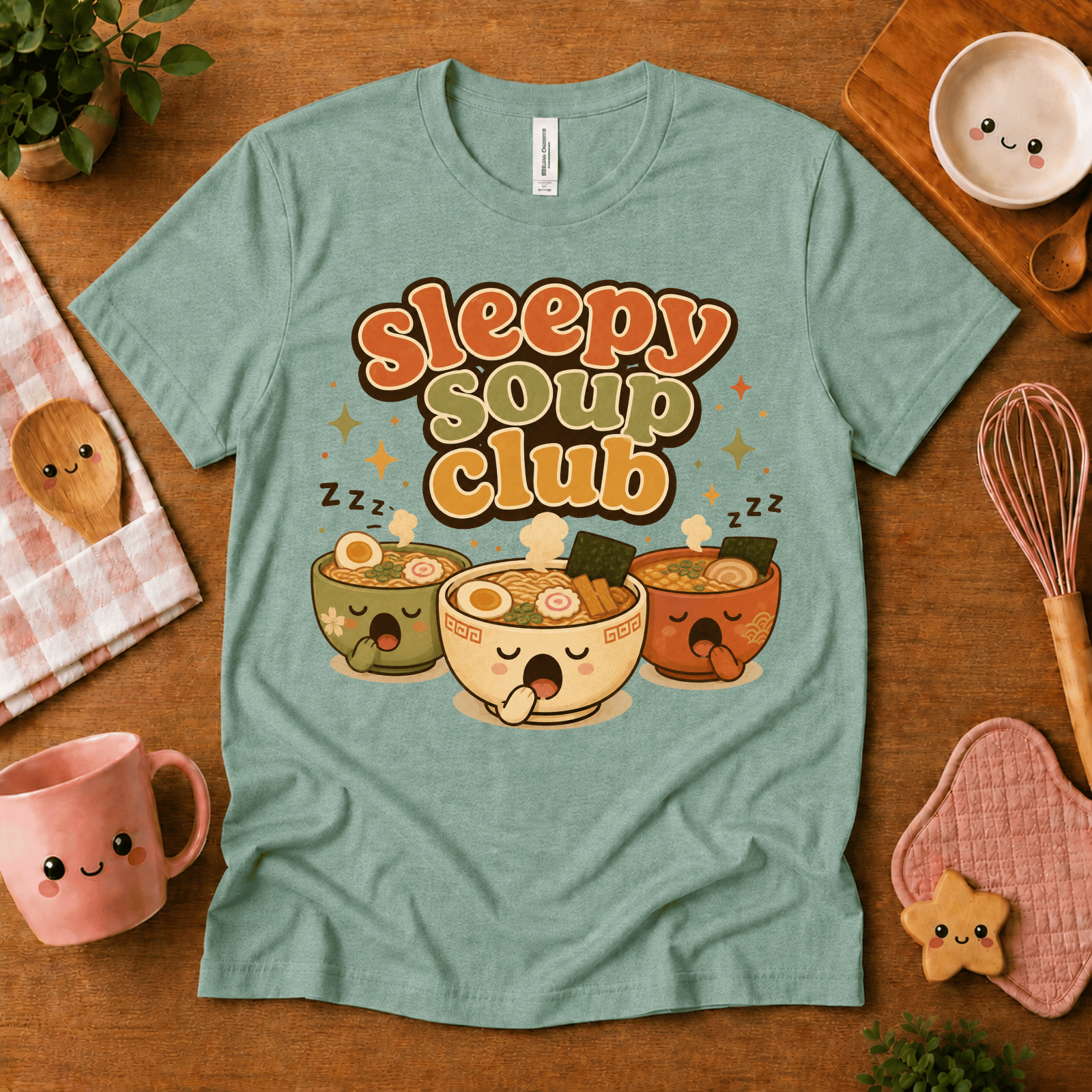 Sleepy Soup Club cute food graphic t-shirt cozy flat lay in heather sea green.