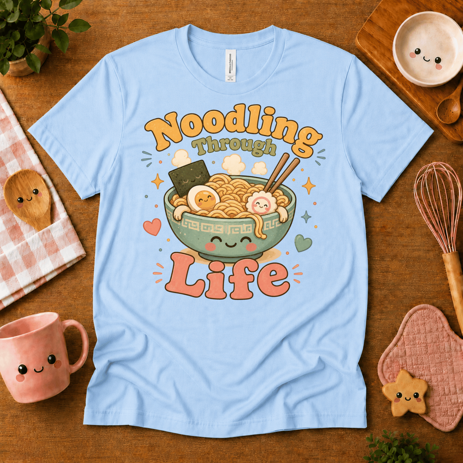 Noodling Through Life cute food graphic t-shirt cozy flat lay in baby blue.