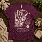 Cat Observing cute animal graphic t-shirt cozy flat lay in maroon.