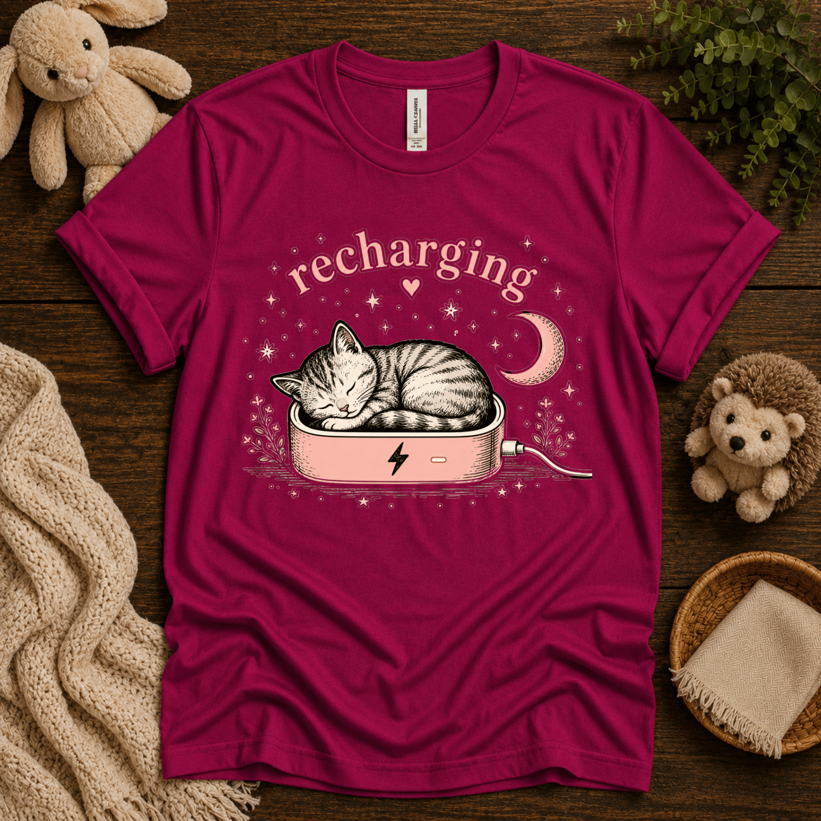 Recharging Cat cute animal graphic t-shirt cozy flat lay in berry.