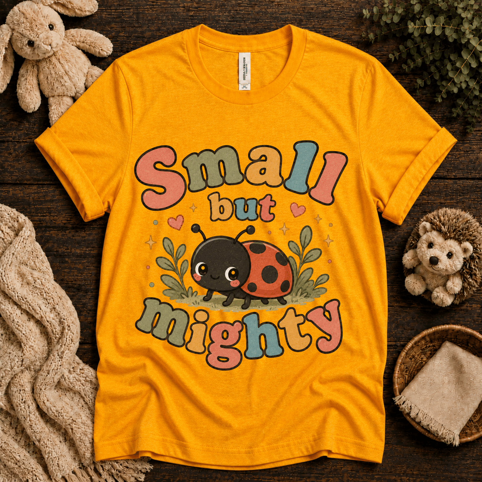Small But Mighty cute animal graphic t-shirt cozy flat lay in gold.