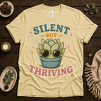 Silent But Thriving funny plant graphic t-shirt cozy flat lay in natural.