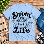 Sippin' on Life cute coffee graphic t-shirt cozy flat lay in baby blue.