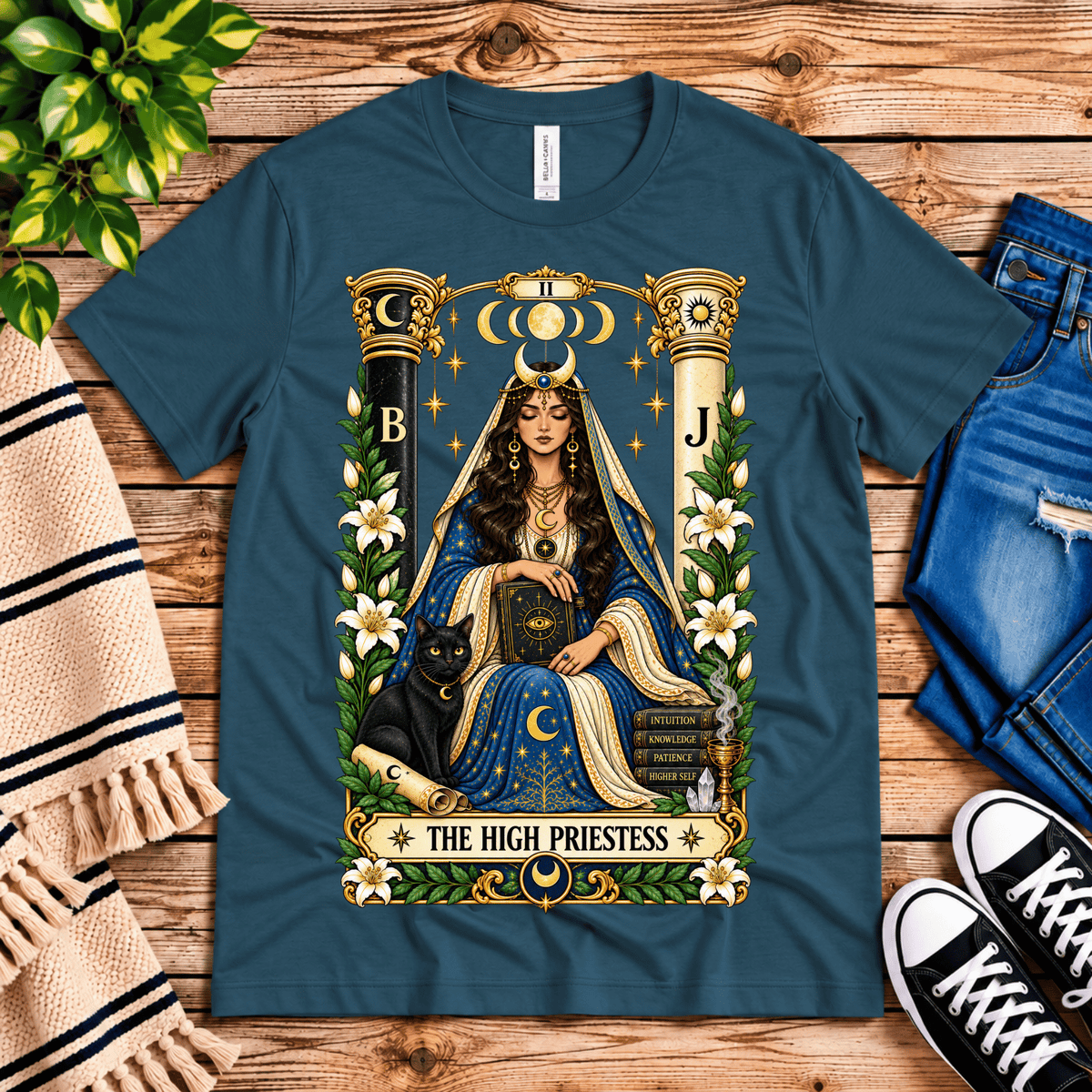 The High Priestess tarot card graphic t-shirt cozy flat lay in deep teal.