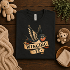 A folded mockup of Winging It cute animal graphic t-shirt in vintage black.