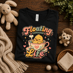 A folded mockup of Floating Through Life graphic t-shirt in vintage black.
