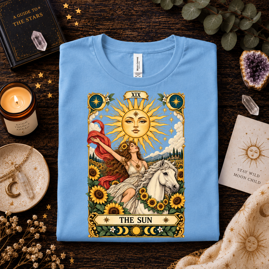 A folded mockup of The Sun tarot card graphic t-shirt in baby blue.
