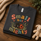 A folded mockup of Small But Mighty cute animal graphic t-shirt in asphalt.