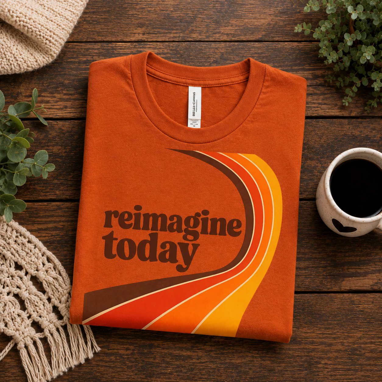 A folded mockup of Reimagine Today inspirational introvert graphic t-shirt in burnt orange.