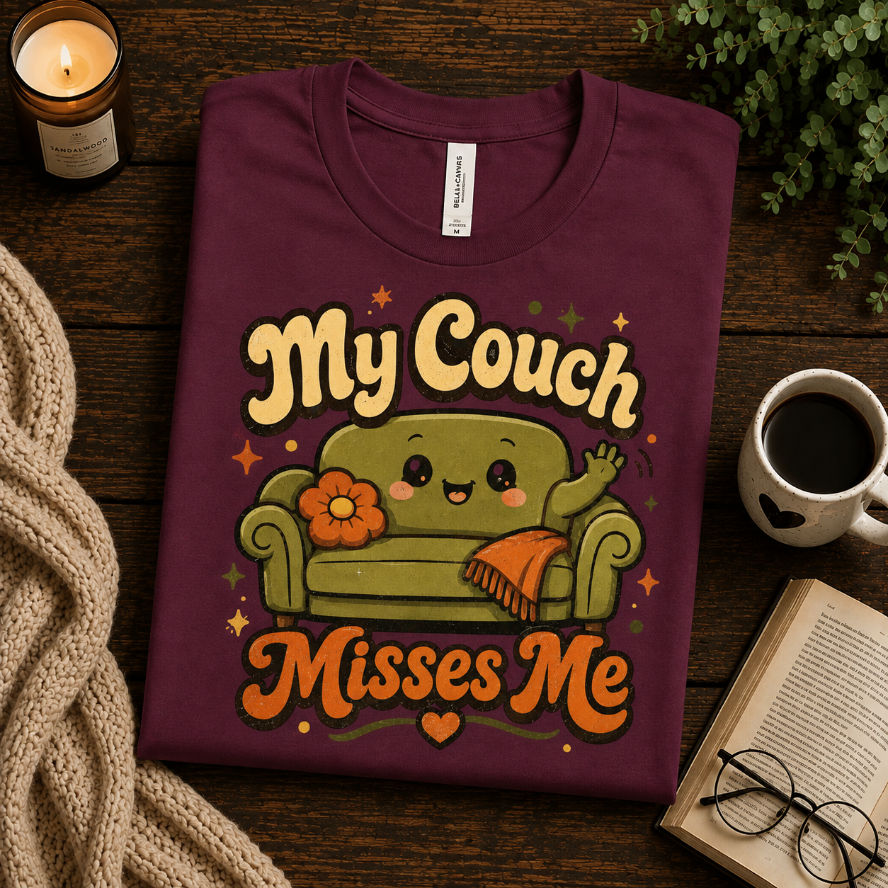 A folded mockup of My Couch Misses Me funny introvert graphic t-shirt in maroon.