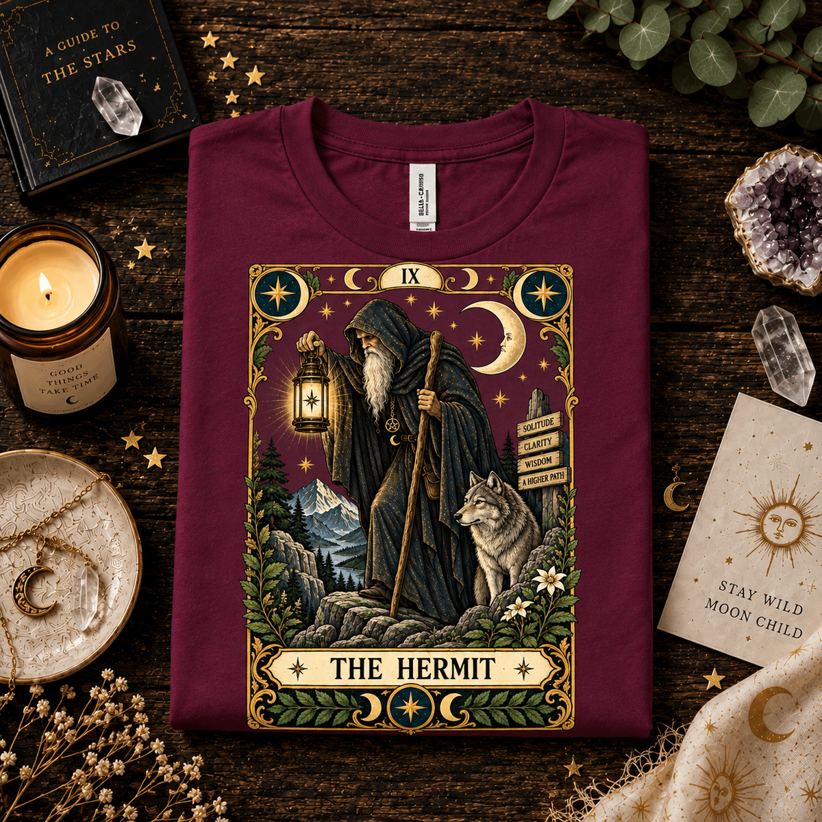 A folded mockup of The Hermit tarot card graphic t-shirt in maroon.