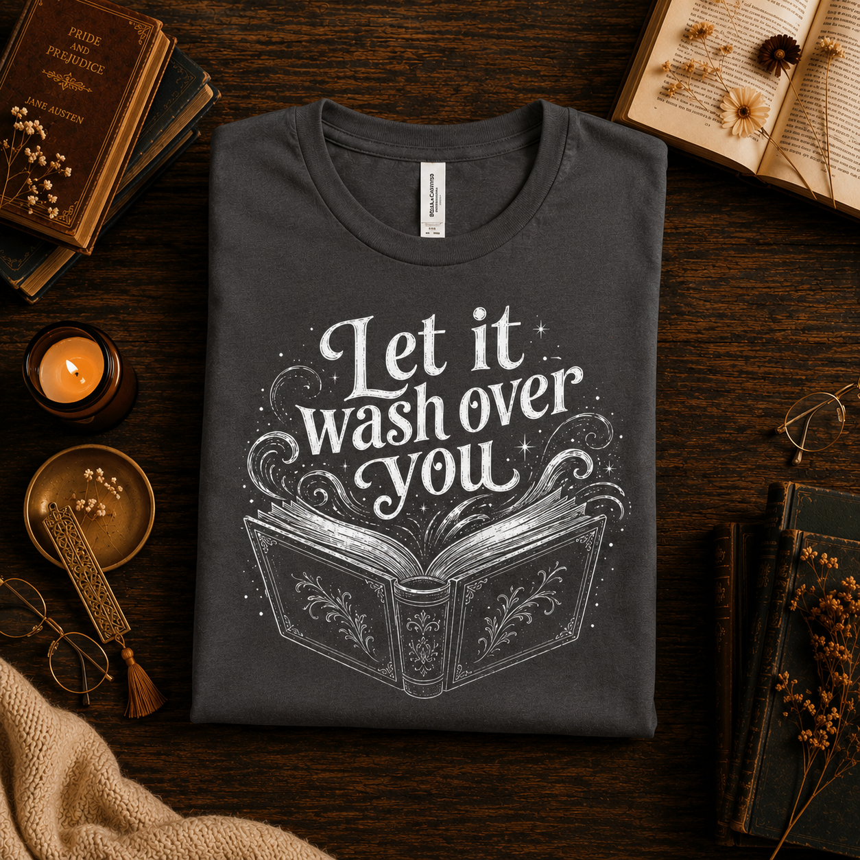 A folded mockup of Let It Wash Over You whimsical book graphic t-shirt in asphalt.