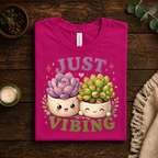 A folded mockup of Succulent Vibing funny plant graphic t-shirt in charity pink.