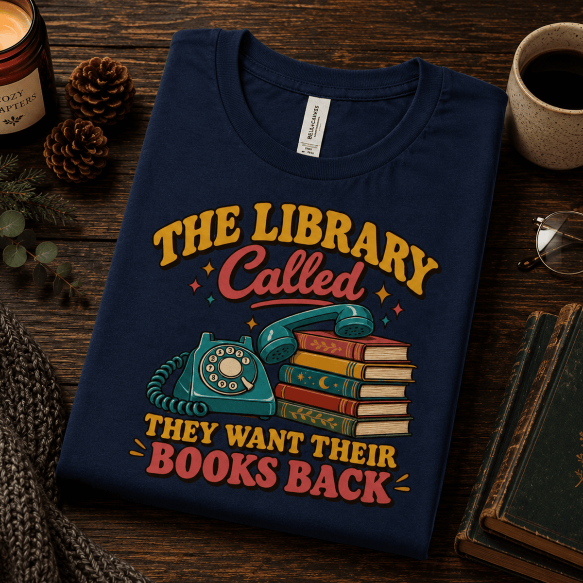 A folded mockup of The Library Called book lovers graphic t-shirt in navy.