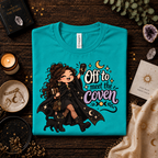 A folded mockup of Off to Meet the Coven witchy celestial graphic t-shirt in heather sea green.