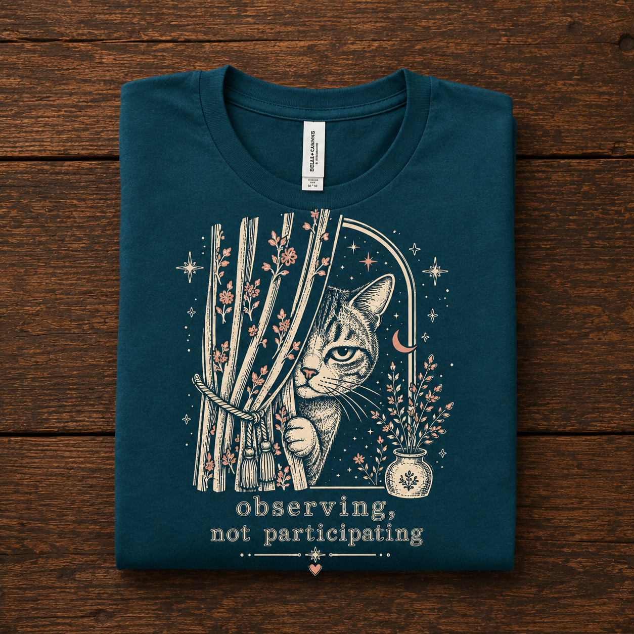 A folded mockup of Cat Observing graphic t-shirt in deep teal.