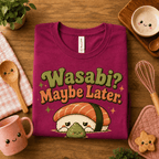 Folded mock up of Wasabi graphic t-shirt in berry, surrounded by small kitchen utensils.