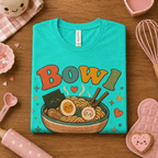 Folded mock up of Bowl Goals graphic t-shirt heather sea green, surrounded by small kitchen utensils.