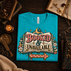 A folded mockup of Booked & Unavailable graphic t-shirt in heather sea green.