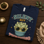 A folded mockup of Silent But Thriving cute plant graphic t-shirt in navy.