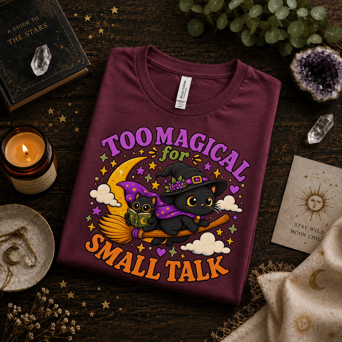 A folded mockup of Too Magical cute celestial graphic t-shirt in maroon.