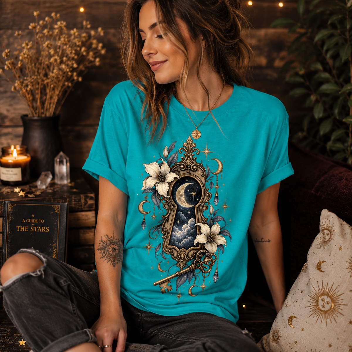 A woman wearing a heather sea green Cosmic Keyhole whimsical celestial graphic t-shirt.