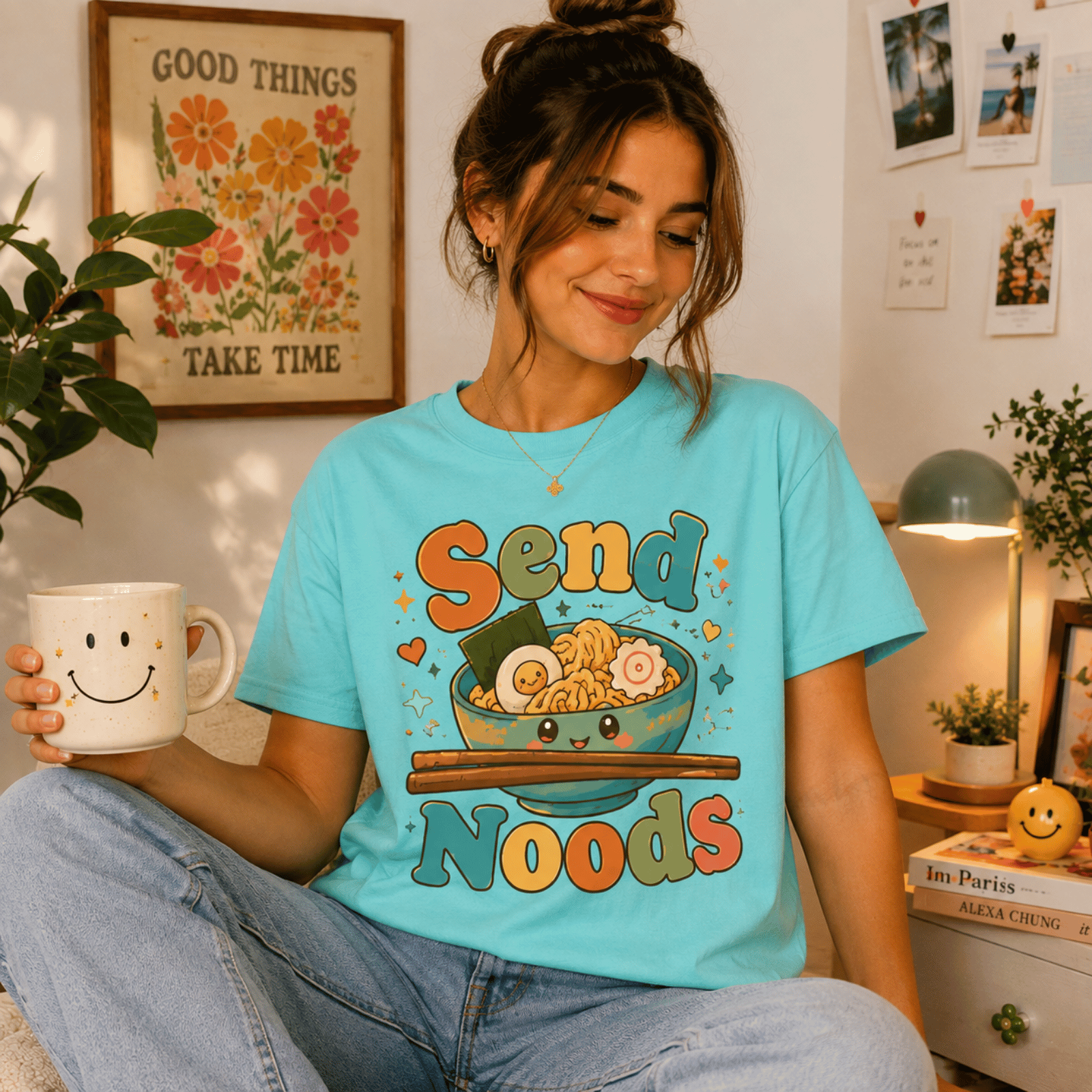 Woman wearing Send Noods graphic t-shirt in aqua sitting at a desk, taking a break with coffee.