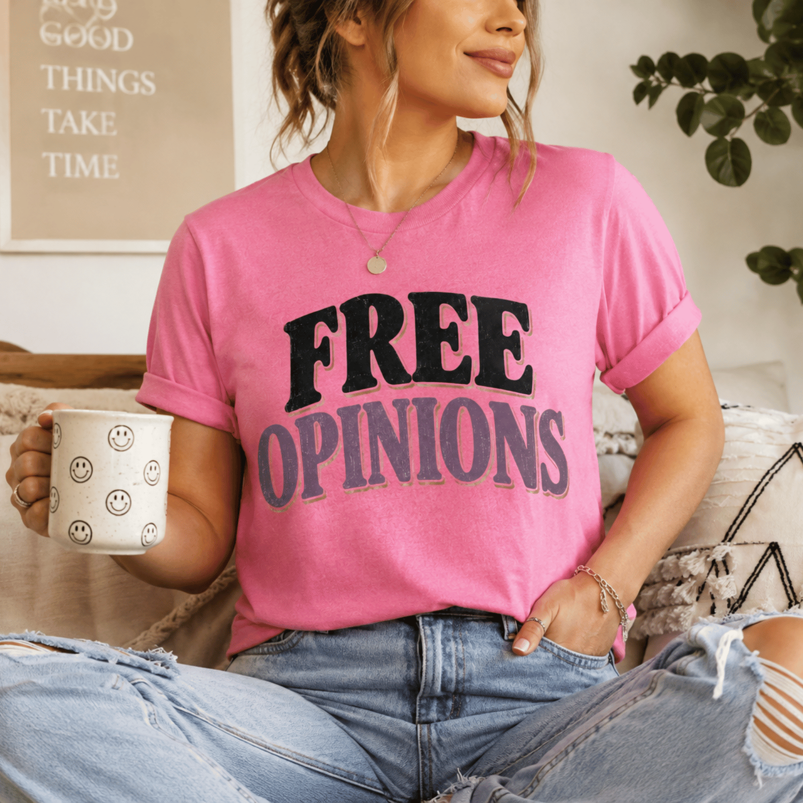 A woman wearing a charity pink Free Opinions funny introvert graphic t-shirt drinking coffee.