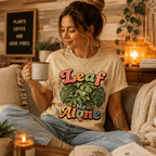 A woman wearing a natural Leaf  Me Alone funny plant graphic t-shirt drinking coffee.