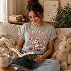 A woman wearing an athletic heather Overthink Cat cute animal graphic t-shirt reading a book.