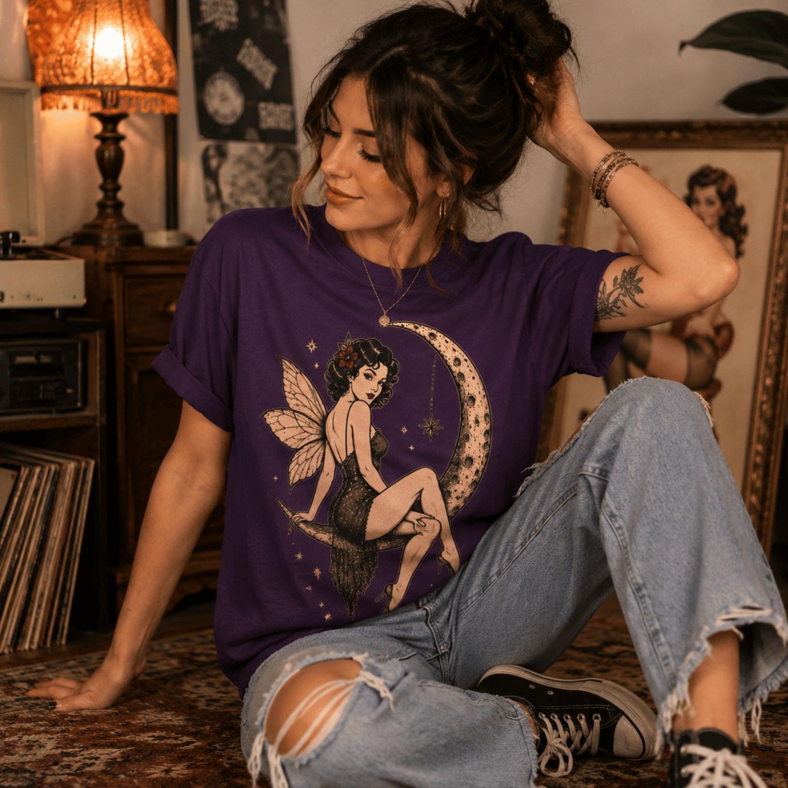 A woman wearing a team purple Red Rose Moon graphic pinup fairy t-shirt listening to her records in her living room.