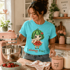 Woman in cute kitchen with pink accessories wearing Always Free graphic t-shirt in aqua.