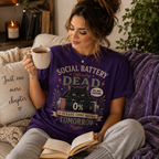 A woman wearing a team purple Social Battery funny introvert graphic t-shirt drinking coffee.