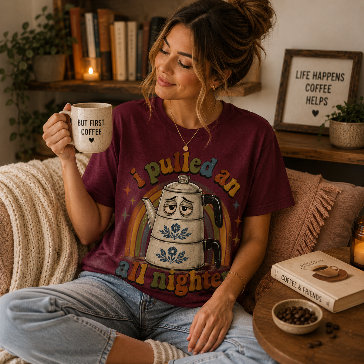 A woman wearing a maroon All Nighter retro graphic t-shirt drinking coffee.