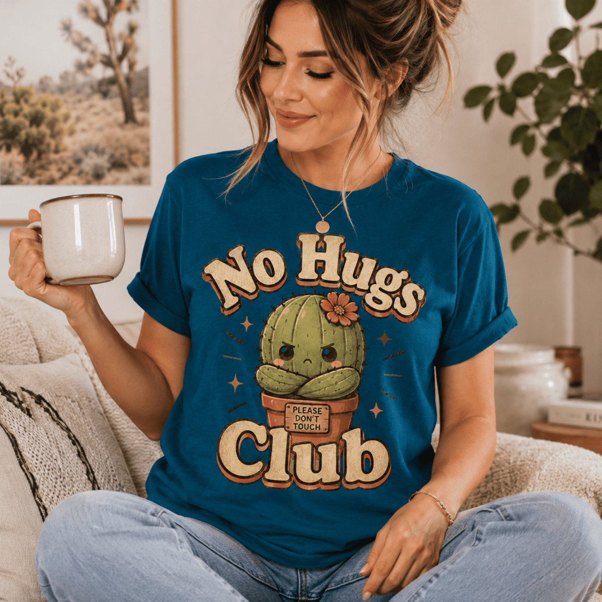 A woman wearing a deep teal No Hugs Club funny cactus graphic t-shirt drinking coffee.
