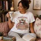 A woman wearing a white Available For Judgement graphic t-shirt drinking coffee.