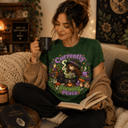 A woman wearing an evergreen Currently Brewing cute witchy graphic t-shirt drinking coffee.