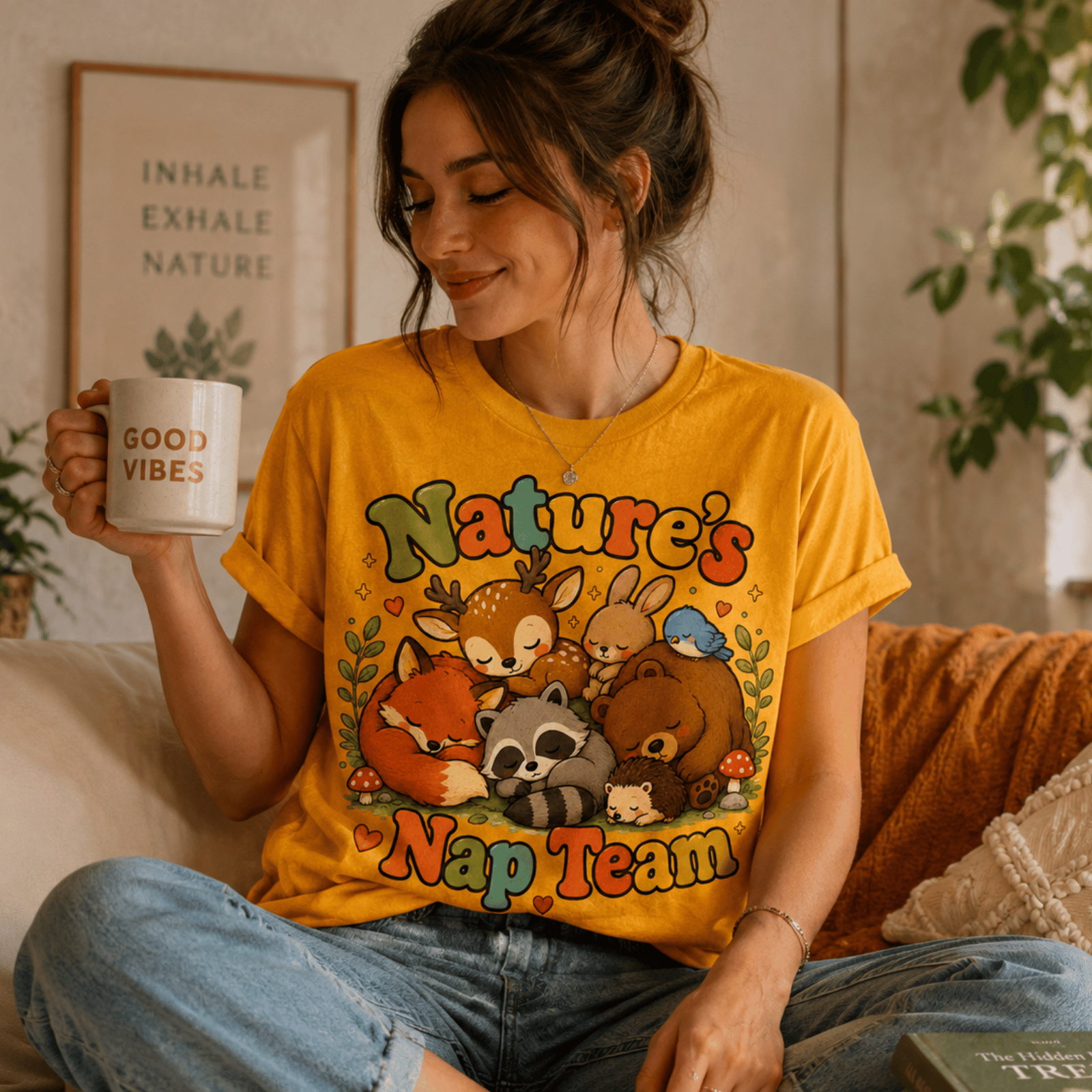 A woman wearing a gold Nature's Nap Team cute animal graphic t-shirt drinking coffee.