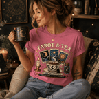 A woman wearing a charity pink Tarot & Tea charity pink graphic t-shirt drinking coffee.