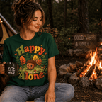 A woman wearing a evergreen Happy Alone cute nature graphic t-shirt sitting next to a campfire.