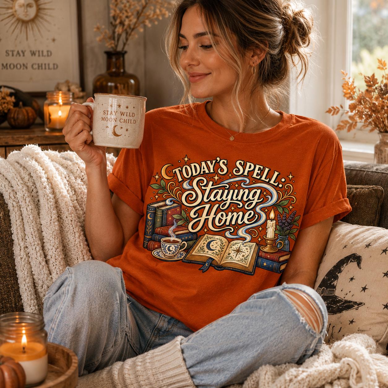 A woman wearing a burnt orange witchy celestial graphic t-shirt drinking coffee.