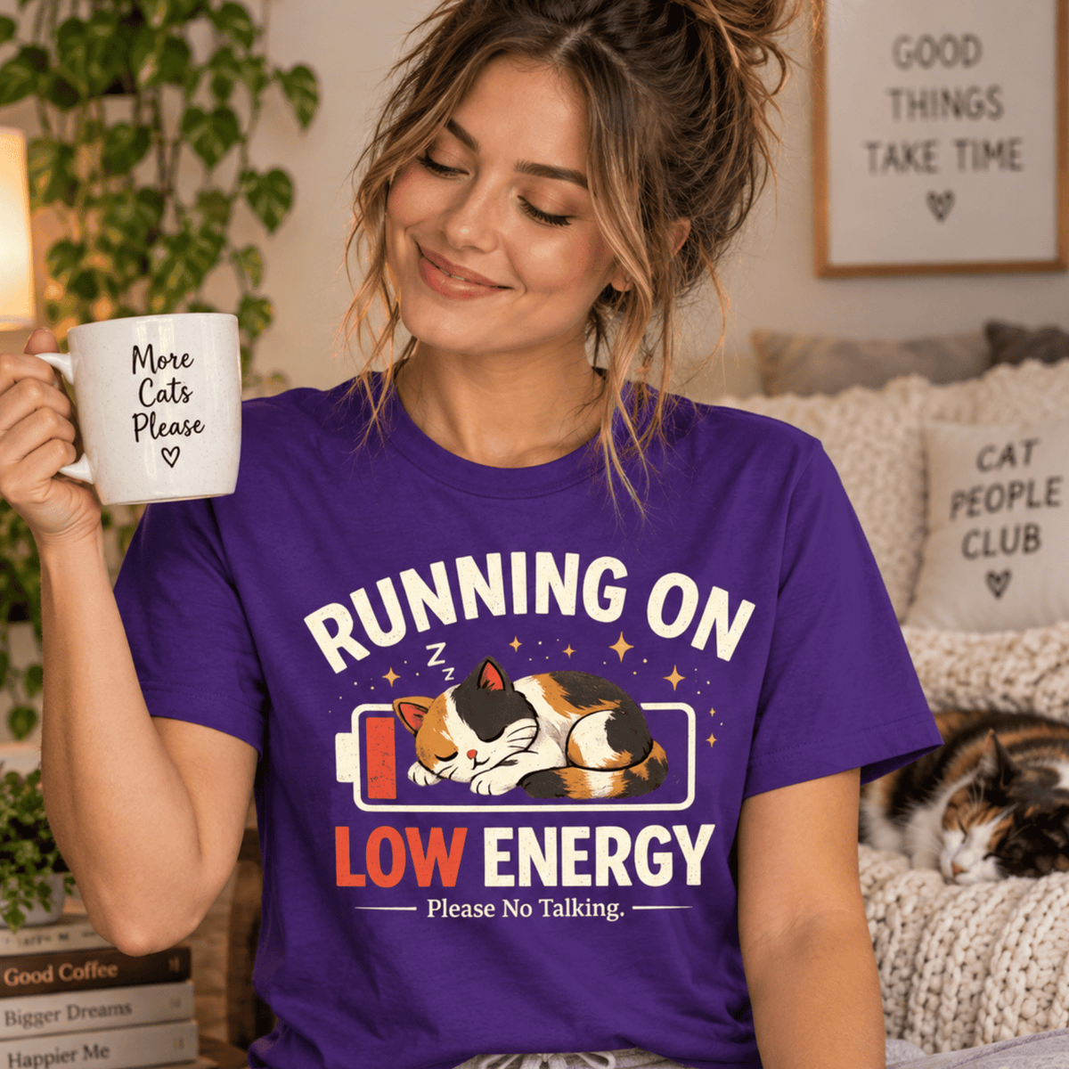 A woman wearing a team purple Low Energy Cat cute animal graphic t-shirt.