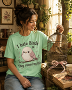 A woman wearing a mint I Hate Birds graphic t-shirt playing with her pet bird.