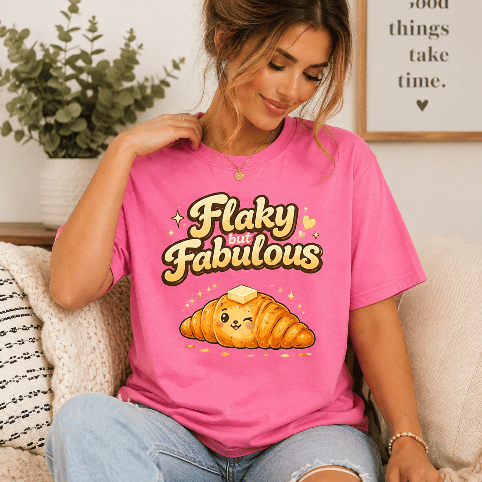 Woman wearing Flaky But Fabulous graphic t-shirt in charity pink sitting on couch.