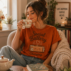 Woman drinking tea in her living room wearing a burnt orange Social Battery of Tea.