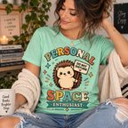 A woman wearing an a mint Personal Space Enthusiast graphic t-shirt.