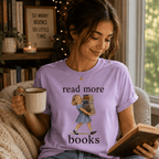 A woman wearing a lilac Read More vintage book graphic t-shirt reading a book.