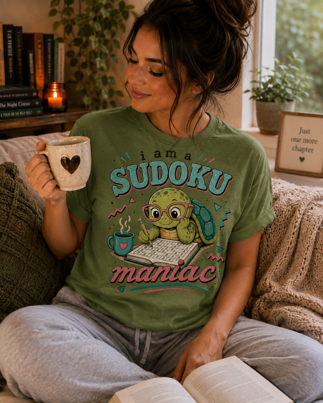 A woman wearing a leaf Sudoku Maniac funny introvert graphic t-shirt drinking coffee.